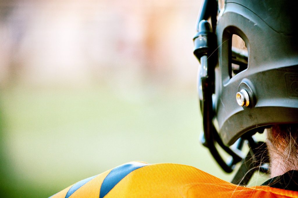 A close up of the helmet and ball on a football field.