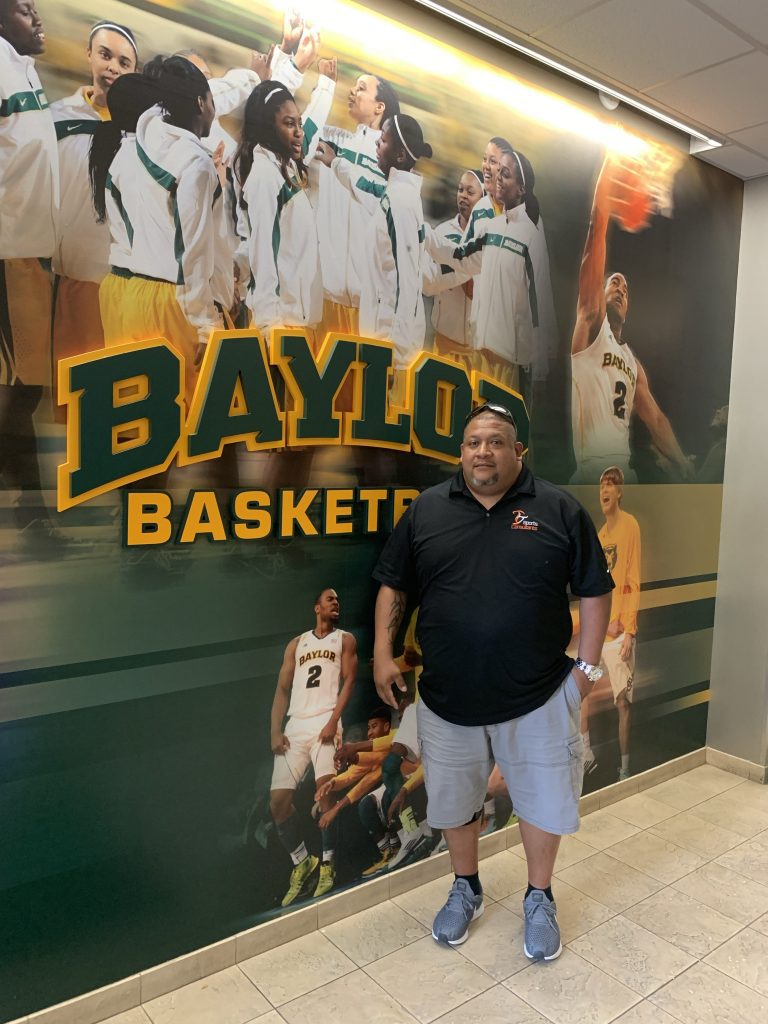 A man standing in front of a baylor basketball poster.