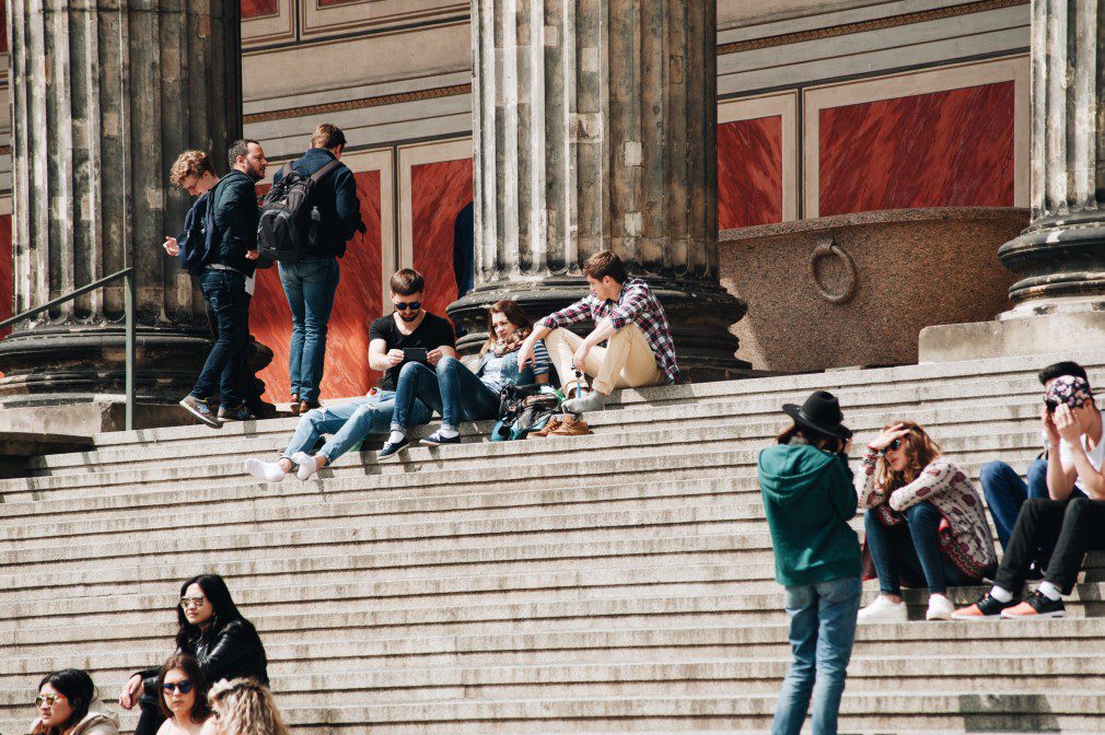 A group of people sitting on steps near a pillar.