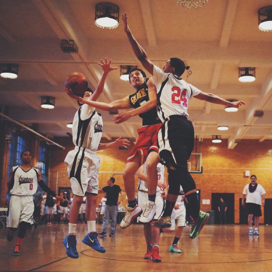 A group of young men playing basketball on a court.