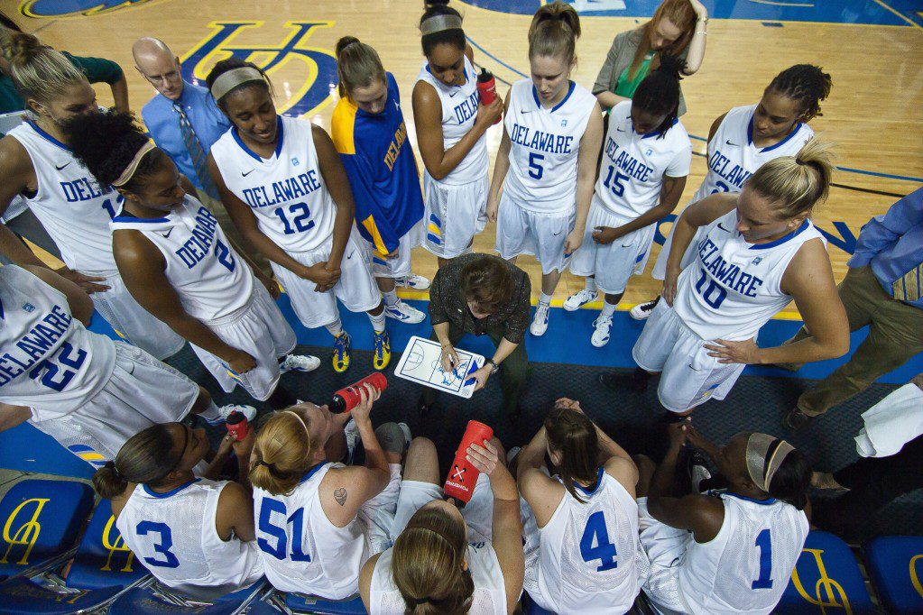 A group of women in white jerseys standing on top of a basketball court.