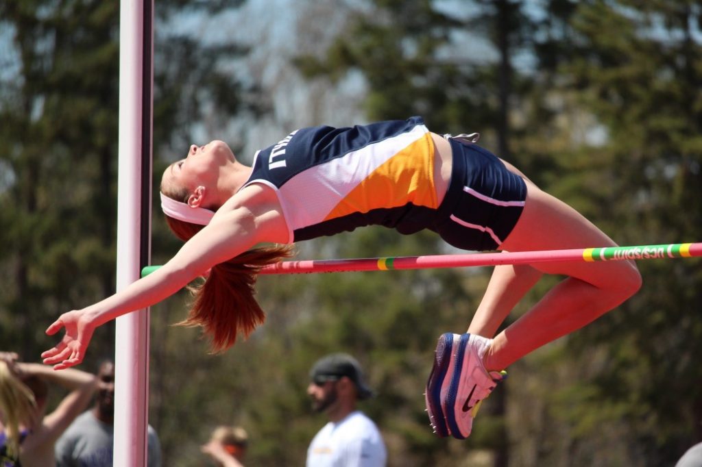 A woman is jumping over the bar in an event.